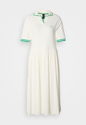 Robe polo blanche côtelée avec une jupe évasée, accent vert sur le col et les manches, présentant un logo rond sur la poitrine.