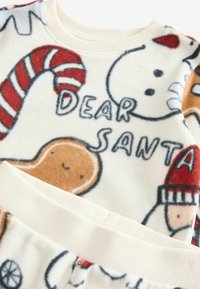 Ensemble de pyjama en polaire pour enfants avec des motifs festifs, comprenant des bonhommes de neige et des pains d'épice, en crème, avec des poignets et une taille côtelés.