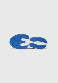 Semelle de chaussure avec une base blanche et un motif de traction en caoutchouc bleu, dotée d'une surface texturée pour une meilleure adhérence. Des rainures notables améliorent la flexibilité.