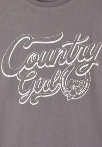 Szara bawełniana koszulka z białym, postarzanym napisem "Country Girl" oraz akcentem w postaci kwiatowego wzoru. Miękka faktura materiału.