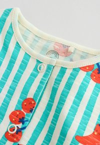 Detský odev s tyrkysovými a bielymi pruhmi so zapínaním na cvoky, s malými červenými a oranžovými potlačami ovocia a zvierat na látke.
