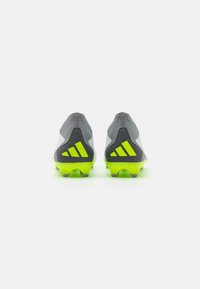 Scarpette da calcio grigie con accenti neri e verde neon. Tomaia texturizzata e design a profilo basso. Presenta un distintivo logo a tre strisce sul tallone.