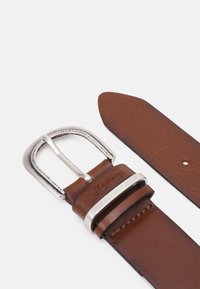 Brauner Ledergürtel mit einer silbernen rechteckigen Schnalle, die eine Naht entlang des Riemens aufweist und "Mustang" auf das Leder geprägt ist.