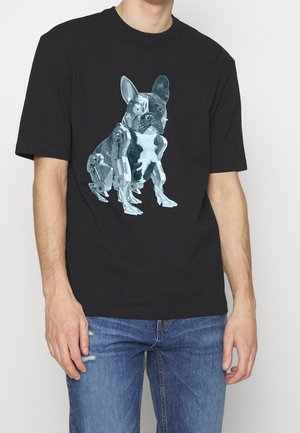 T-shirt noir avec un graphisme d'un bouledogue français combiné à des pièces robotiques, porté par une personne en jean bleu.