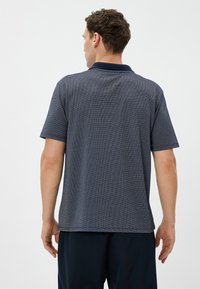 Polo de color azul marino con un patrón texturizado, mangas cortas y un cuello de contraste. Diseñado para un ajuste relajado con un dobladillo recto.