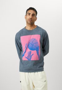 Langermet grå skjorte med et rosa og blått grafisk motiv av hender som rekker ut etter en basketball, laget av mykt stoff med en avslappet passform.