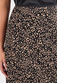 Gonna nera con un motivo a stampa leopardata in beige. Il tessuto presenta una superficie liscia e la vita è rifinita con un bordo semplice.