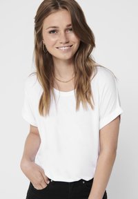 Hvit kortermet T-skjorte med rullede ermer og rund hals, laget av mykt stoff, kombinert med svarte høyt midjejeans.
