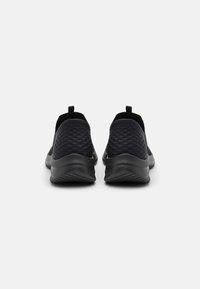 Sorte slip-on sko med teksturert mesh-overdel, rund tå, og en fleksibel gummisåle med en lett hæl.