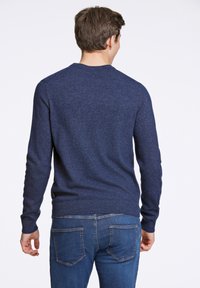 Marineblauer gestrickter Pullover mit Rundhalsausschnitt und langen Ärmeln, mit geripptem Saum und Bündchen, getragen mit Jeans.
