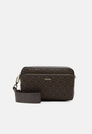 Mörkbrun Calvin Klein axelväska med upprepande CK-logomönster, framficka med dragkedja och justerbar tygrem med logotypprägling.