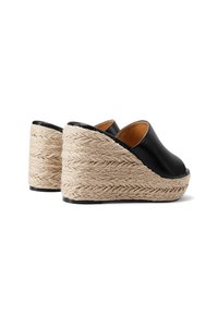 Sandali wedge neri in pelle con una base a trama simile alla juta, caratterizzati da una parte superiore liscia e un design aperto sul retro per una facile calzata.