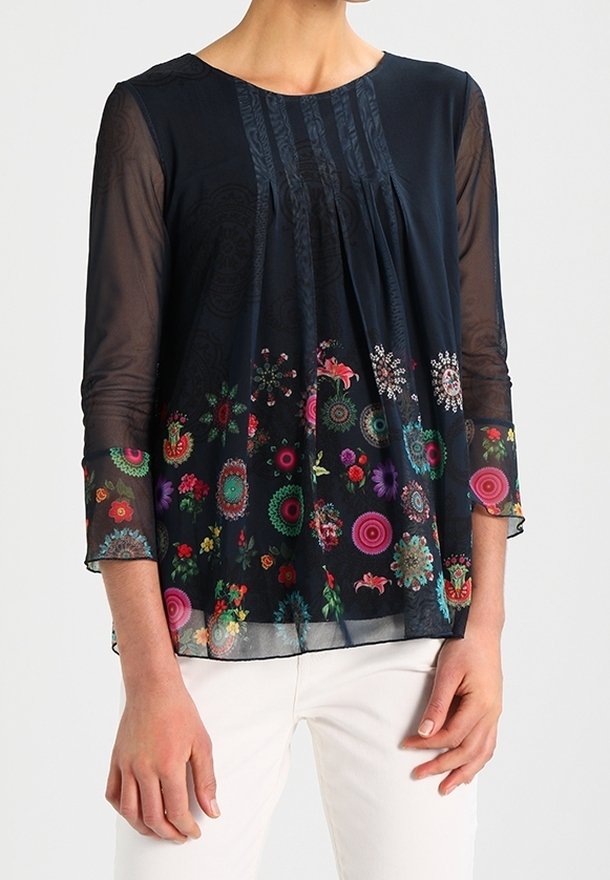 Blouse navy avec des manches longues transparentes, un devant plissé et un motif floral aux couleurs vives. Tissu doux et léger avec des détailsintriqués.