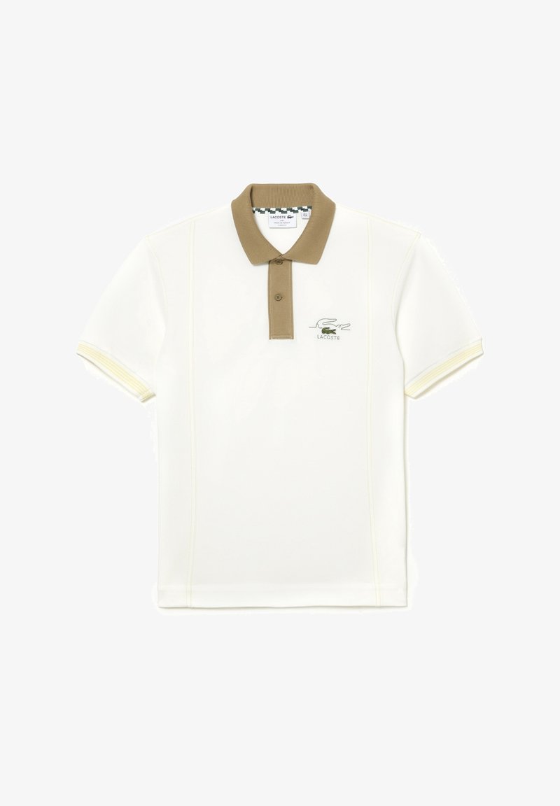 Polo shirt blanc avec un col marron clair, des manches courtes et des accents jaunes. Présente un logo Lacoste vert sur la poitrine.