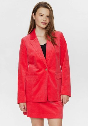 Rode corduroy blazer met een enkele knoop, twee voorzakken en een opstaande kraag. Gecombineerd met een bijpassende rok, beide in vergelijkbare stof.