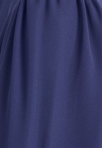 Tissu bleu marine foncé avec une texture douce et lisse, présentant des drapés délicats et un éclat subtil, adapté à la conception de vêtements.