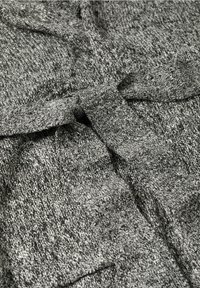 Vêtement en maille grise présentant un motif texturé avec un détail noué à la taille. Le tissu est doux avec un aspect tissé.