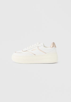 Vit sneaker med tjock, texturerad sula och en metallisk roséguldsaccent på hälen. Har en slät läderövre och snörning.