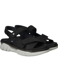 Sandales en suede noir avec des brides croisées et des fermetures Velcro ajustables. Semelle synthétique blanche contournée avec un design texturé.