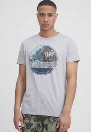 Grå bomulds T-shirt med et cirkulært grafisk tryk af palmer og teksten "CLAIM YOUR RIGHTS" i blå. Korte ærmer og rund hals.