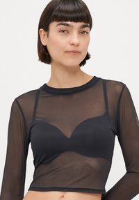 Czarna, długoskrzydłowa bluzka z siatki o okrągłym dekolcie, z dopasowaną wewnętrzną warstwą i przezroczystym zewnętrznym materiałem, oferująca lekki wygląd.