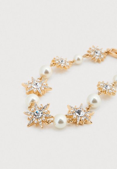 Βραχιόλι σε χρυσό τόνο με αστέρια από στρας και λευκά μαργαριτάρια, συνδεδεμένα με μικρούς μεταλλικούς συνδέσμους.