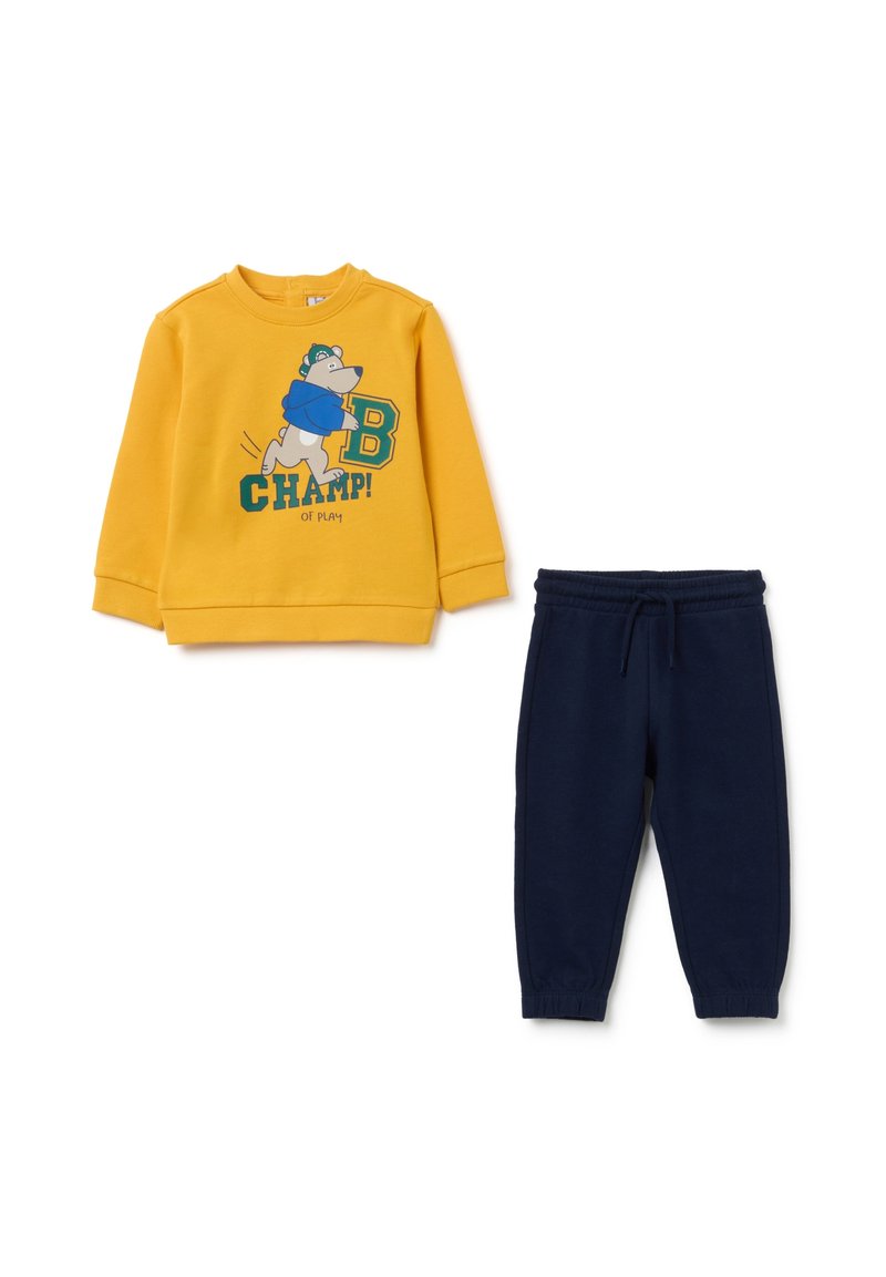 Geel sweatshirt met een beerafbeelding en groene tekst, gecombineerd met marineblauwe joggers met een elastische tailleband. Zacht katoen.