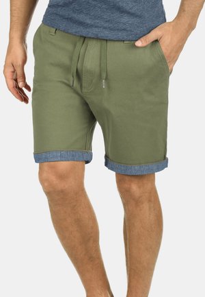 Olivgröna shorts med uppvikta denimkantar, snörning i midjan och sidofickor. Tillverkade av lätt material för avslappnad användning.