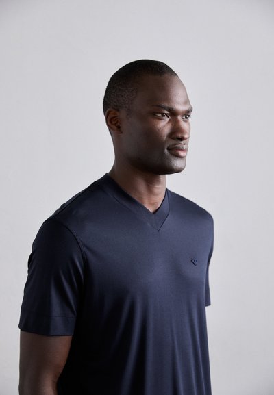 Navy v-neck t-shirt made from smooth fabric, featuring short sleeves and a subtle logo on the left chest. Simple, modern design.