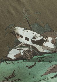 Grafische t-shirt met een verwoeste witte vliegtuigwrak op groen gras, omringd door palmbomen en gestileerde loof in aardetinten.