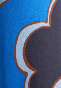 Abstracte stof met een mix van blauwe, donkergrijze en lichtblauwe vormen omlijnd in bruin, met een gladde textuur en levendige kleuren.