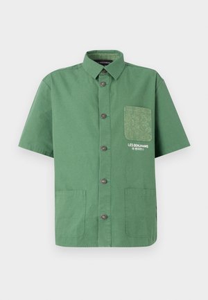Chemise verte à manches courtes en coton, avec un devant à boutons, deux poches avant, et une poche à motif sur le côté gauche.