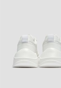 Bílé tenisky s hladkým koženým svrškem, zakulaceným podpatkem, texturovanou gumovou podrážkou a plochými šnúrkami. Zpevněná zadní část se záložkou pro easier obouvání.