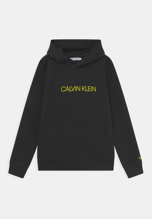 Sort hættetrøje med "Calvin Klein" i gul tekst på brystet og et lille gult "ck" på venstre ærmekant. Ingen person er vist.