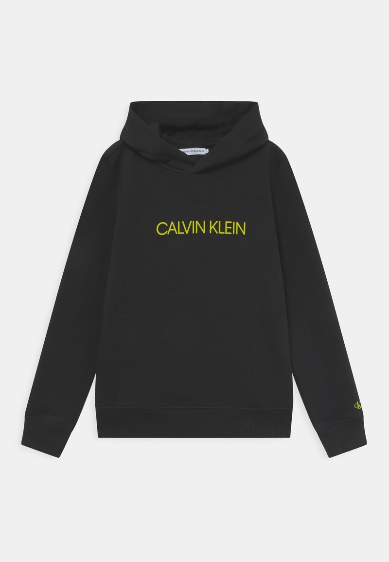 Sweat à capuche noir avec "Calvin Klein" en texte jaune sur la poitrine et petit "ck" jaune sur le poignet de la manche gauche. Aucun personne n'est visible.
