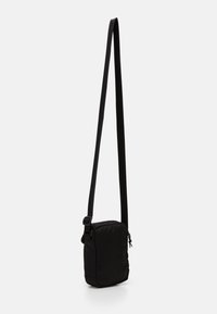 Borsa a tracolla nera con forma rettangolare, tracolla regolabile, tessuto morbido e chiusura con zip dotata di un robusto tirante.