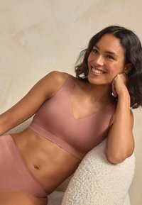 Heleroosa bralette V-kaelusega ja laiade rihmadega, sobitatud kõrge vöökohaga pükstega, mõlemad sileda ja matt-textuuriga.