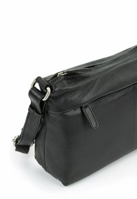 Borsa in pelle nera con finitura texturizzata, chiusura con zip e tracolla regolabile. Caratterizzata da accessori in tonalità argento e un dettaglio con tasca laterale.