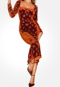 Sukienka z aksamitu w palonym pomarańczu z kwadratowym dekoltem, bufkami, haftem floralnym i rozkloszowanym dołem. W połączeniu z czółenkami na spiczastym obcasie.