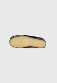 Black shoe sole with a textured, light beige interior. The bottom is smooth and slightly curved, featuring no visible patterns or accents.