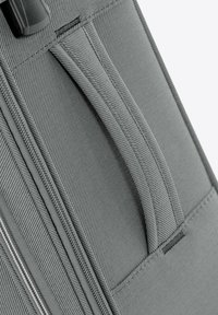 Grauer Stoffkoffer mit einem robusten Stoffgriff, horizontalen Steppnähten, einem Reißverschluss und einer strukturierten Oberfläche.