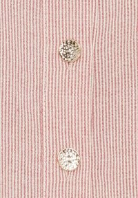 Rød og hvid stribet stof med to metalliske knapper med en struktureret overflade. Smalle lodrette striber skaber et skarpt mønster.