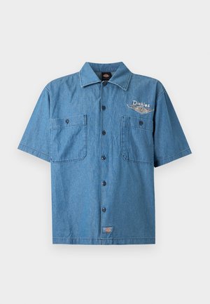 Chemise à manches courtes en denim bleu avec col, deux poches poitrine, et broderie du logo "Dickies" sur le haut à gauche.