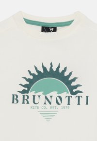 Weißes Baumwoll-T-Shirt mit Rundhalsausschnitt, das ein grünes Sonnenmotiv und den Text "BRUNOTTI KITE CO. EST. 1979" zeigt. Weicher Stoff, lockere Passform.