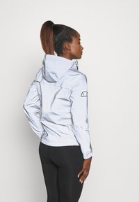 Hellblau, leichtgewichtiges Jacket mit Kapuze, elastischen Bündchen und einem gestickten Akzent an den Ärmeln. Glattes, wasserabweisendes Material.