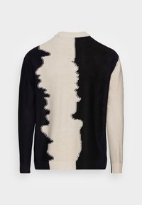 Suéter de punto con diseño dividido en negro y crema, con detalles texturizados, cuello redondo y puños acanalados.