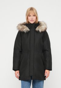 Czarna parka z kapturem wyłożonym futrem, z zamkiem błyskawicznym, kieszeniami po bokach i elastycznym wykończeniem w talii. Tkanina ma gładką teksturę.