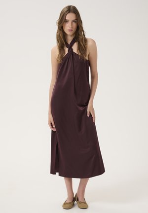 Burgundy halter maxi dress with a knot detail at the neckline, side slit, and smooth fabric. Model paired with olive-colored flats.