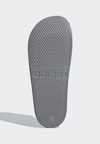 Sole di sandaletti grigi in gomma con superficie testurizzata caratterizzata da un motivo a diamante e la parola "adidas" impressa in modo evidente.