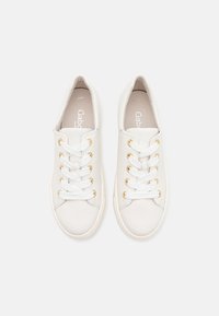 Baskets en cuir blanc avec œillets dorés, lacets blancs plats, bout rond et texture lisse. Logo de la marque contrastant visible à l'intérieur.